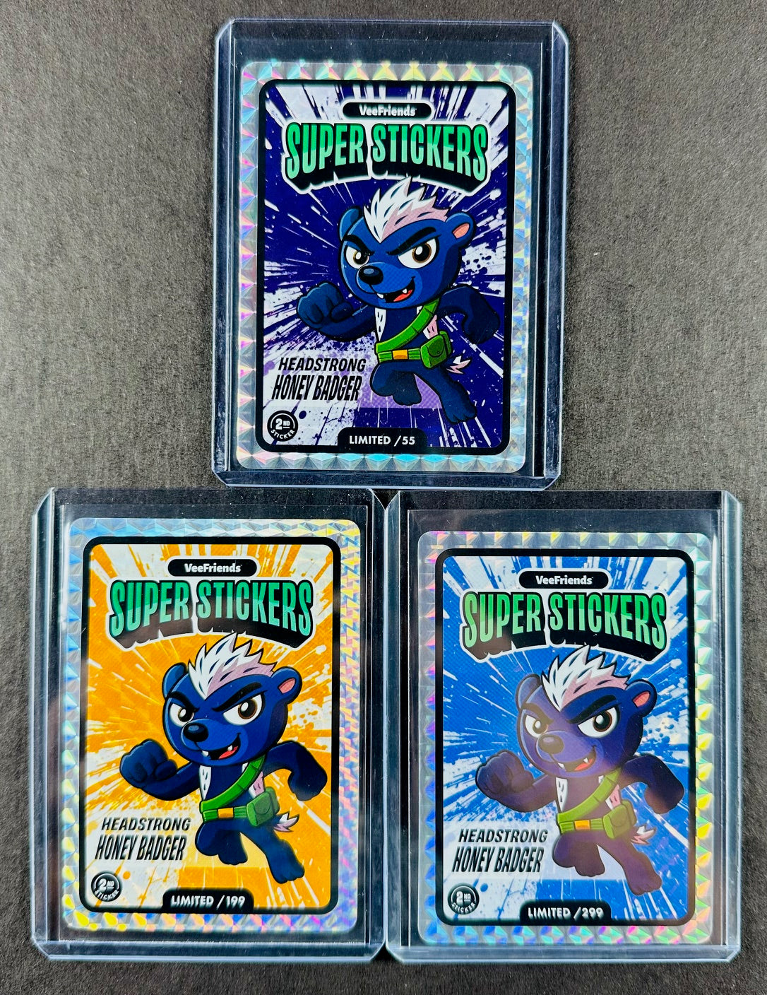 VeeFriends Super Stickers – Headstrong Honey Badger 3-Card Bundle – Purple Splash /55 + Orange Splash /199 + Manga Clouds /299